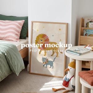 Op de afbeelding: Een rechthoekige houten lijst met een poster met een cartoonillustratie van een grote gele leeuw en een kleinere blauwe kat, beide met kleurrijke manen, tegen een lichte achtergrond met gele en blauwe sterren en de tekst poster mockup.