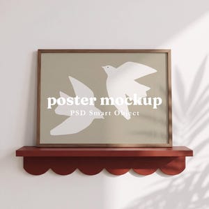 May include: A rectangular wooden frame containing a beige poster with two white bird silhouettes. The text "poster mockup" and "PSD Smart Object" are centered on the poster. The frame rests on a dark red scalloped shelf with text above and below.