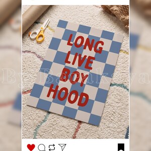 May include: A rectangular print featuring a blue and off-white chequered pattern with the red text LONG LIVE BOYHOOD centred on the surface. The print is displayed alongside a pair of white and yellow scissors on a textured white surface.