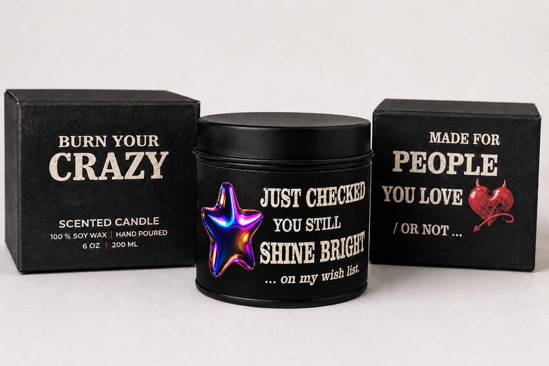 Puede incluir: Vela perfumada negra con un dise&ntilde;o de estrella met&aacute;lica y el texto "Just Checked You Still Shine Bright". La vela est&aacute; en una lata negra, con una caja a juego que dice "Burn Your Crazy". La otra caja dice "Made for People You Love".