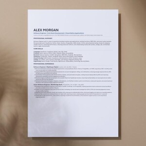 以下が含まれることがあります： ニュートラルな背景に「ALEX MORGAN」と題された白い履歴書。履歴書には、職務要約、コアスキル、職務経験のセクションが含まれています。テキストは、読みやすいクリーンなフォントです。