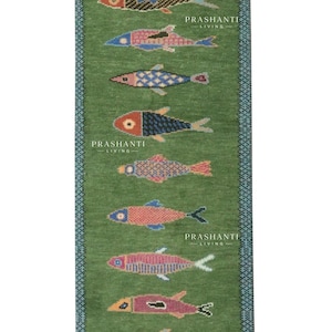 May include: Green rectangular rug with a repeating pattern of colorful fish. The fish are in various colors, including pink, blue, and orange, and are arranged vertically. The rug has a blue border and the text "PRASHANTI LIVING".