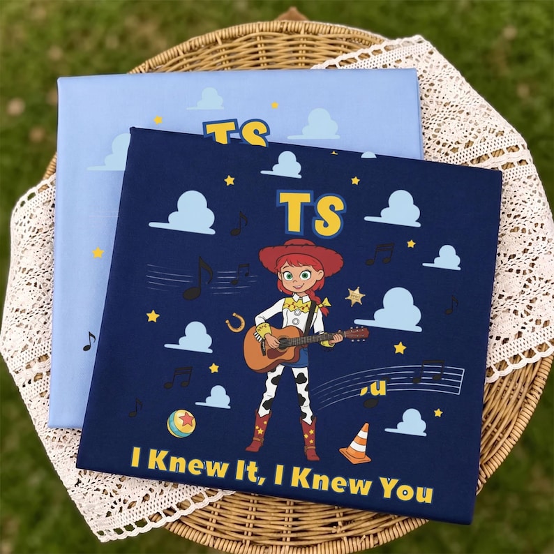 Peut inclure: Un panneau en tissu carr&eacute; bleu fonc&eacute; repr&eacute;sentant un personnage de dessin anim&eacute; aux cheveux roux jouant de la guitare acoustique, entour&eacute; de nuages blancs, d'&eacute;toiles jaunes, de notes de musique, d'un ballon et d'un c&ocirc;ne, avec le texte TS et I KNEW IT, I KNEW YOU.