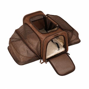 May include: A brown pet carrier with expandable mesh sides and a top opening. The carrier features multiple zippered mesh panels for ventilation, a soft cream-colored interior lining, and an integrated black safety tether with a metal clasp inside.