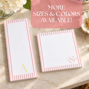 May include: Two white paper notepads with pink striped borders. The tall rectangular notepad features a gold letter A, while the square notepad displays a monogram with the letters ASB. Text overlay reads: MORE SIZES & COLORS AVAILABLE!