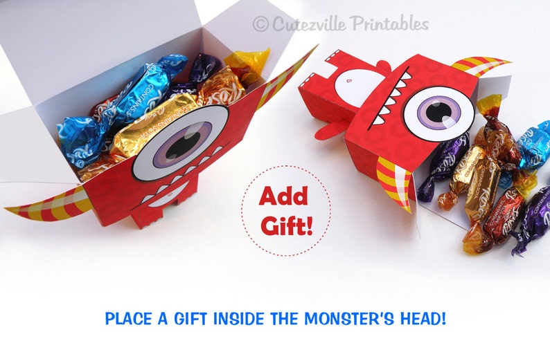 May include: Red monster-shaped box with a large eye and yellow and red stripes. The box is open and filled with wrapped candies. The text "Add Gift!" is written in a red circle. The text "PLACE A GIFT INSIDE THE MONSTER'S HEAD!" is written in blue at the bottom of the image.