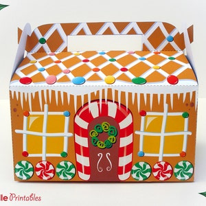 Op de afbeelding: Een gingerbreadhuis-vormige cadeaubox met een snoepstokdeur, een krans en een wit glazuur dak. De doos heeft een handvat aan de bovenkant en is versierd met kleurrijke snoepjes.