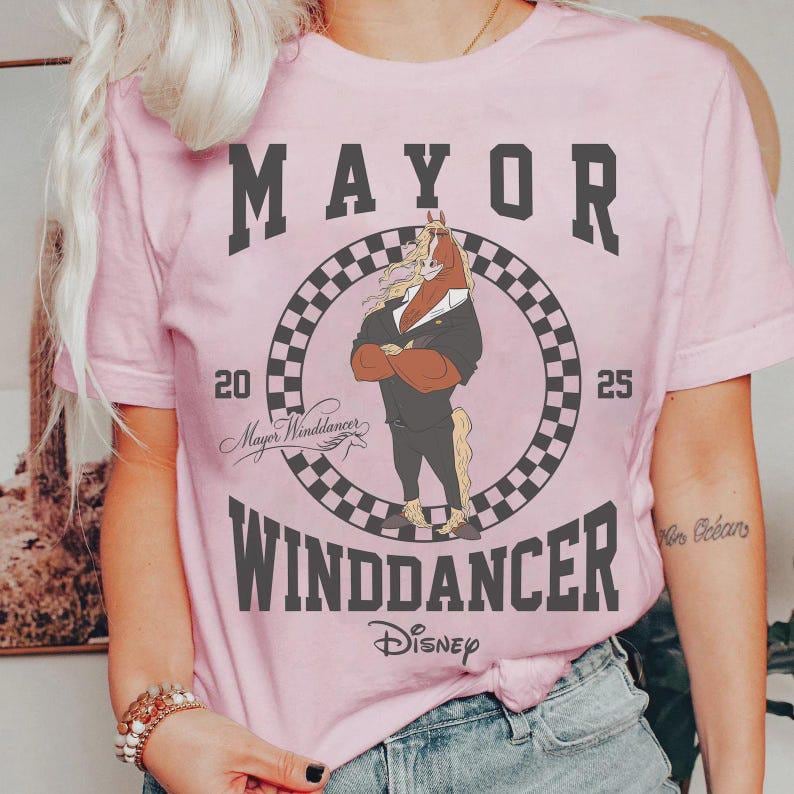 May include: Pink t-shirt featuring a cartoon horse in a suit, with the text "MAYOR WINDDANCER" and "Disney". The design includes a checkered circle and the numbers "20" and "25".