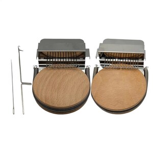 May include: Two circular wooden darning looms with silver metal components and spring mechanisms, accompanied by a long metal needle and a hooked metal tool. The looms feature a flat, light-colored wood surface and a row of metal hooks at the top.