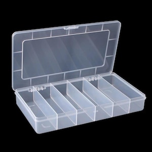 May include: A rectangular, clear plastic storage container with a hinged lid. The interior is divided into six separate compartments by fixed vertical dividers. The box features a secure latch mechanism on the front edge and a smooth finish.