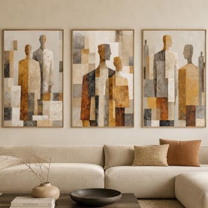 Puede incluir: Un conjunto de tres cuadros de pared enmarcados con figuras humanas abstractas compuestas por formas geométricas en tonos ocre, beige, gris y blanco. Cada impresión rectangular muestra siluetas estilizadas dispuestas en una composición en capas.