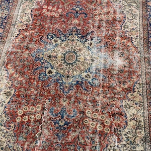 May include: A rectangular area rug featuring a central medallion design with intricate floral and vine patterns in shades of red, navy blue, and cream. The rug has a wide decorative border with repeating geometric and botanical motifs throughout.
