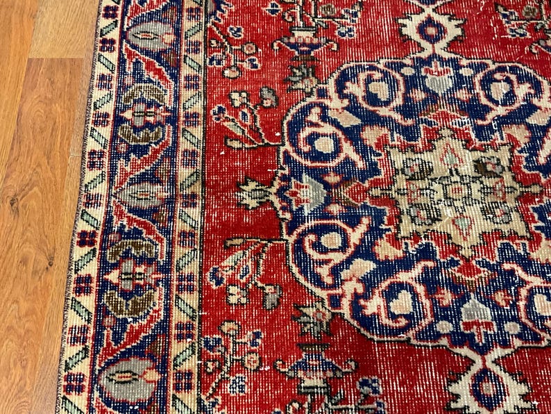 Pu&ograve; includere: Un tappeto rettangolare caratterizzato da un campo rosso vivace con un grande medaglione blu centrale. Il design include intricati motivi floreali e geometrici in tonalit&agrave; crema, blu navy e verde salvia, rifinito con un bordo decorativo.
