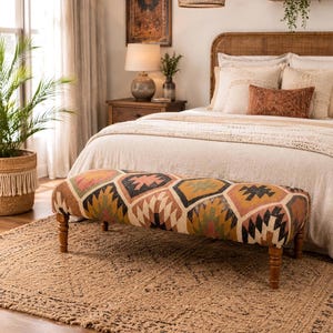 May include: A bedroom scene featuring a patterned bench with wooden legs, placed on a textured jute rug. The bed has a woven headboard and is adorned with pillows and a terracotta-coloured lumbar pillow. A woven pendant light hangs above the bed.