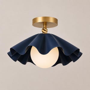 May include: A ceiling light fitting featuring a matte navy blue, ruffled, wide-brimmed shade and a central spherical white glass globe. The fitting is attached to a circular brass-toned canopy with an adjustable swivel joint at the top.