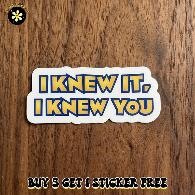 May include: A rectangular die-cut sticker with a white border featuring the text I KNEW IT, I KNEW YOU in bold yellow letters with a dark blue outline. The sticker has a matte finish and is positioned against a dark brown wood grain background.