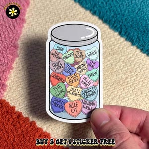 May include: A sticker featuring a clear glass jar filled with colorful heart-shaped candies. Each candy is inscribed with text including Baby, The Mistake, Babydou, The Score, Wellsy, Grace Ivers, John Logan, Sabrina James, The Deal, Gorgeous, John Tucker, Darlin, The Goal, Allie Hayes, Dean Di Laurentis, Garrett Graham, Stupid Jackass, Allie Cat, and Hannah Wells.