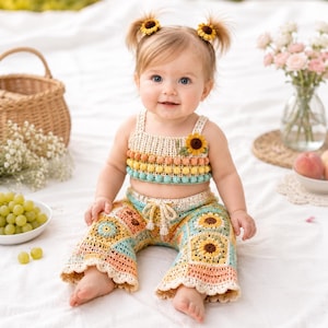 May include: A two-piece crochet outfit consisting of a cropped tank top and flared pants. The top features horizontal rows of bobble stitches in peach, yellow, and teal with a sunflower appliqué. The pants are made of multi-colored granny squares.