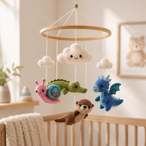 May include: A hanging mobile featuring a circular wooden frame with white strings suspending crocheted figures including a pink snail, a green crocodile, a brown otter, a blue dragon, and three white clouds with embroidered facial features.