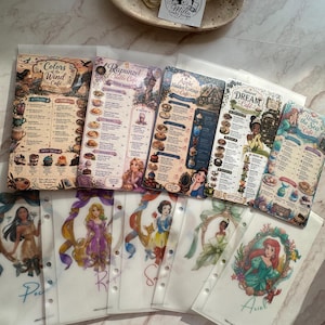 May include: A collection of five rectangular printed menu cards featuring Disney-themed cafe designs, including Colors of the Wind, Rapunzel Castle, Apple Hidden Cottage, Dream, and Under the Sea, alongside five translucent binder inserts with character illustrations.