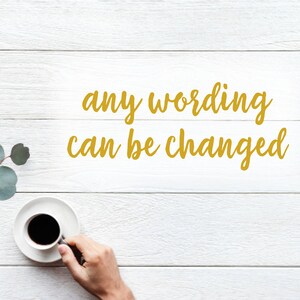 Puede incluir: Una taza de caf&eacute; negro sobre un platillo blanco, sostenida por una mano, descansa sobre una superficie de madera blanca. El texto "any wording can be changed" est&aacute; escrito en oro. Hojas de eucalipto en la esquina superior izquierda.