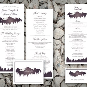 May include: Wedding stationery set featuring a mountain and forest design in shades of purple and white. The set includes an invitation, ceremony program, menu, thank you card, and table setting card.
