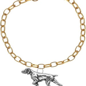 May include: Gold-toned chain bracelet with a lobster clasp closure. A silver-colored pendant in the shape of a dog is suspended from the chain. The dog pendant is a detailed representation of a Pointer breed.