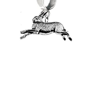 May include: A silver charm depicting a running hare. The charm is designed with intricate detail, showing the hare in motion. It has a loop for attaching to a bracelet or necklace. The hare is shown mid-leap.
