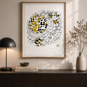 May include: Abstract art print in a gold frame. The artwork features yellow and black circular shapes with a scribbled black line design. The print is signed in the bottom right corner. The artwork is displayed on a dark brown cabinet.