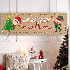 May include: A rectangular horizontal sign with a tan background featuring a green Christmas tree, two cartoon elves, and a string of colourful lights. The text reads WE'RE BACK LET THE FUN BEGIN in red letters, with a small elf icon between the words.