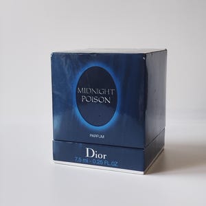 May include: A square, dark blue perfume box featuring a central glowing oval design. The text reads MIDNIGHT POISON, PARFUM, and Dior with the volume 7.5 ml - 0.25 FL.OZ printed on the front. The packaging has a glossy finish and sharp edges.