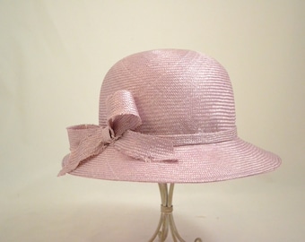 May include: A pink straw hat with a wide brim and a bow on the side.