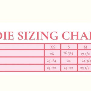 May include: Pink hoodie sizing chart with measurements in inches. The chart includes sizes XS to XL, detailing length, chest, and shoulder measurements. A small illustration of a hoodie is in the upper right corner.