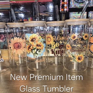 May include: Six clear glass tumblers with bamboo lids and glass straws, each featuring unique sunflower and butterfly designs with inspirational text like In a world full of roses be a sunflower, Always be kind, and You are my sunshine.