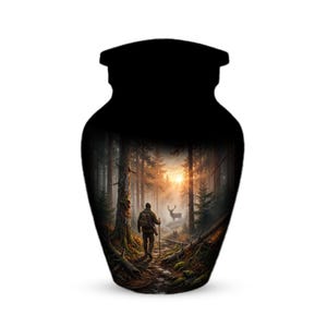 May include: Black urn with a forest scene. The urn features a detailed painting of a person walking on a path through a forest, with a deer in the background and a sunset in the distance. The urn is designed to hold ashes.