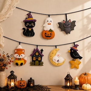 Può includere: Una ghirlanda in feltro a tema Halloween con sette decorazioni pendenti: un gatto nero con cappello viola, un fantasma bianco su una zucca, un pipistrello grigio, una volpe arancione, una casa viola, un coniglio bianco su una luna gialla e un uccello nero su una stella gialla.