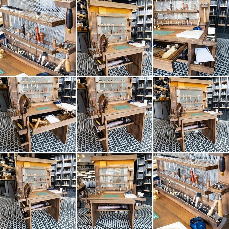 Op de afbeelding: Een houten ambachtelijke werkplek met meerdere planken en laden, gevuld met diverse gereedschappen. De werkplek heeft een ingebouwde bureau met een groene snijmat. De gereedschappen omvatten hamers, tangen en andere ambachtelijke werktuigen.