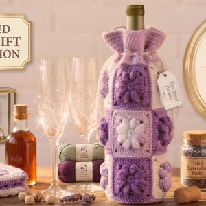 Op de afbeelding: Een samengestelde ambachtelijke cadeaucollectie met een gehaakte wijnfleshoes met bloemmotieven, een glazen pot met gedroogde lavendelbloesem en een download van een haakpatroon. De afbeelding bevat ook haaknaalden, garen en champagneglazen.