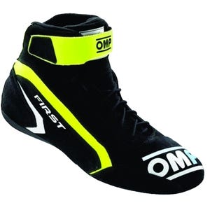 May include: A black high-top racing shoe featuring a bright yellow ankle strap with the OMP logo, black laces, and a white OMP logo on the toe. The side displays the word FIRST in white lettering with a yellow accent stripe along the heel area.