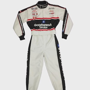 May include: A white and black racing jumpsuit featuring Goodwrench Service branding, a high collar, long sleeves, and a belted waist. The garment displays various sponsor logos including Chevrolet, Snap-on, and Goodyear across the chest and arms.