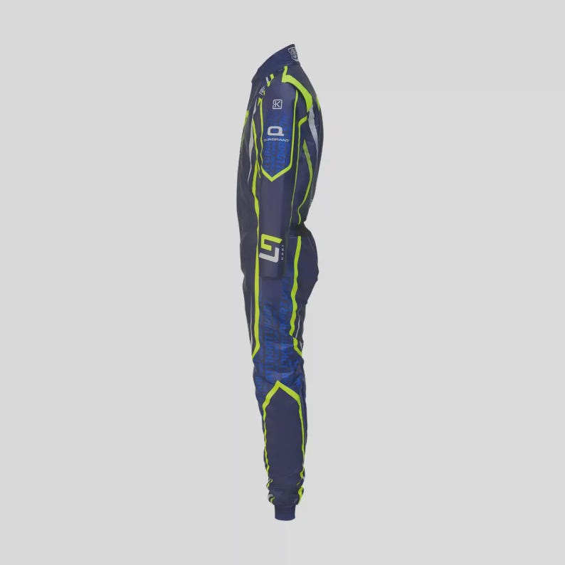 May include: A navy blue racing suit with neon yellow accents. The suit features a full-body design with a high collar and long sleeves. The suit has a blue and yellow geometric pattern on the sleeves and legs. Logos are visible on the chest and arm.
