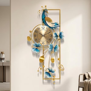 May include: A vertical wall clock featuring a gold-toned circular face with black numerals and hands. The clock is framed by a gold rectangular structure adorned with a blue and gold peacock figure at the top and blue floral accents below.