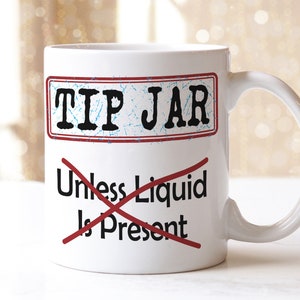 May include: White ceramic mug with a red and blue graphic that says "Tip Jar" with a red line through the words "Unless Liquid Is Present".