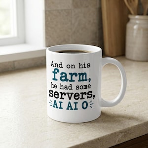 Op de afbeelding: Een witte keramische mok met een handvat, voorzien van zwarte en blauwgroene tekst: And on his farm, he had some servers, AI AI O. De mok heeft een cilindrische vorm en een gladde afwerking voor warme of koude dranken.