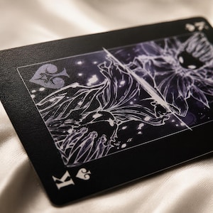 Close up fantasy black playing card with detailed white line art and premium textured finish for collector card decks