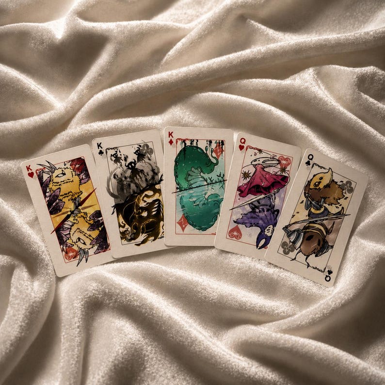 Handmade fantasy playing card set displayed on satin fabric with colorful illustrated face cards and artistic gaming deck aesthetic