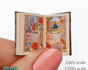 May include: A miniature book with a brown leather cover and colorful illustrations. The book is open to two pages, each with a different scene. The book is being held in a hand with pink nail polish. The text on the page reads "Coming umormore Coun pourmprer".