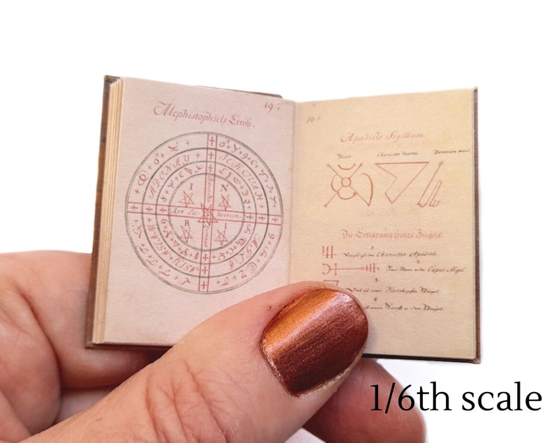 Pu&ograve; includere: Un piccolo libro aperto con illustrazioni in inchiostro rosso e nero. Il libro &egrave; intitolato "Mephistophilis Sigillum" e "Apokalyptic Sigillum". Il libro &egrave; in scala 1/6.