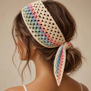May include: A crochet hair bandana featuring a wide band of cream-coloured yarn with a repeating open-work pattern. The design includes horizontal stripes of pastel pink, light blue, and sage green, tied at the back with two pointed ends.