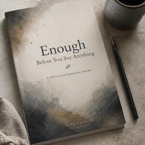 May include: A journal titled "Enough Before You Say Anything" with a watercolor design. The journal is open, with a black pen and a ceramic mug nearby. The journal is from Soft Ground Expressions.